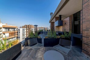 Terraza en la azotea con mobiliario exterior, vista panorámica de la ciudad y una combinación de estilos arquitectónicos de ladrillo y modernos.
