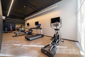 Un gimnasio con cintas de correr, elípticas y equipo de levantamiento de pesas.