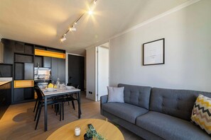 Ein modernes Wohnzimmer mit einem grauen Sofa, einem Holztisch und einem Essbereich mit Tisch und Stühlen.