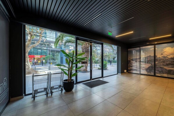Un hall d’entrée spacieux, doté de grandes fenêtres, d’une plante en pot et offrant une vue sur le paysage urbain.