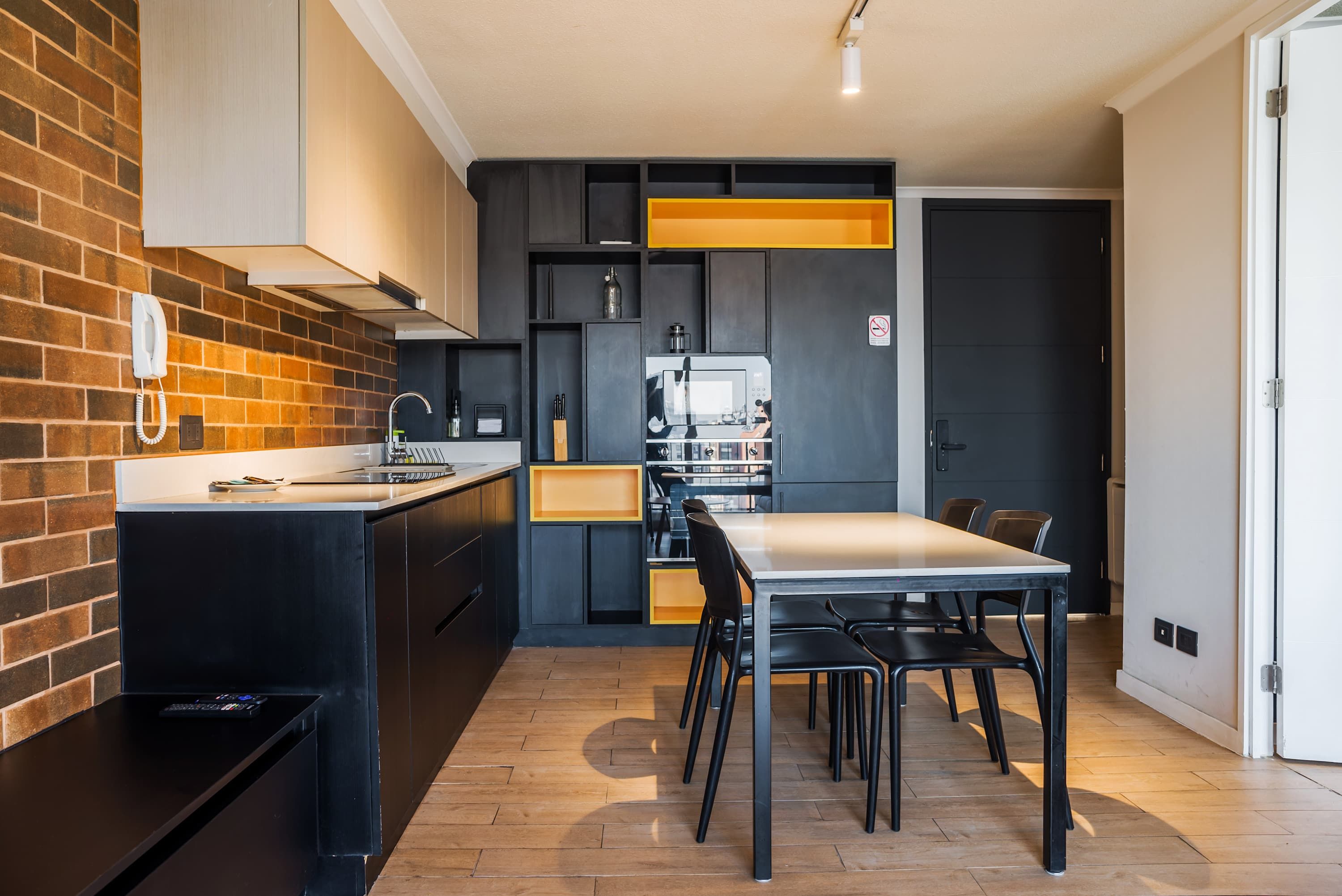 A modern kitchen with a brick accent wall, black cabinetry, and a central island.