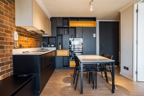 A modern kitchen with a brick accent wall, black cabinetry, and a central island.