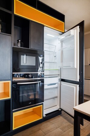 Una cocina equipada con microondas, horno y refrigerador con varios estantes.