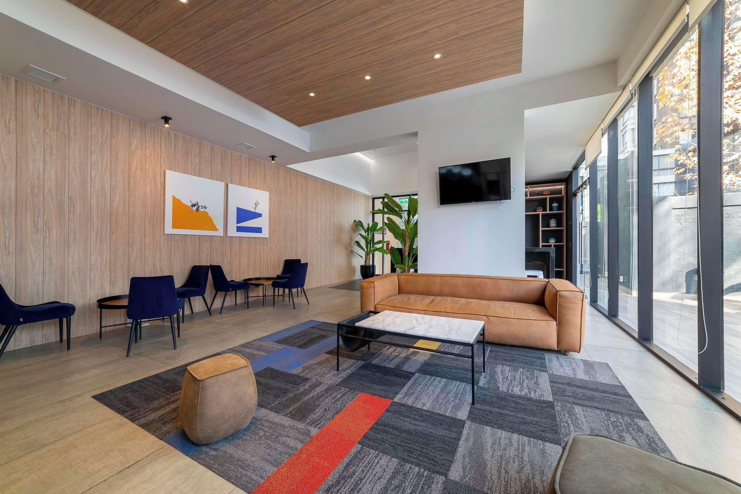 A modern interior with a wooden wall, a sofa, a coffee table, and a TV mounted on the wall.