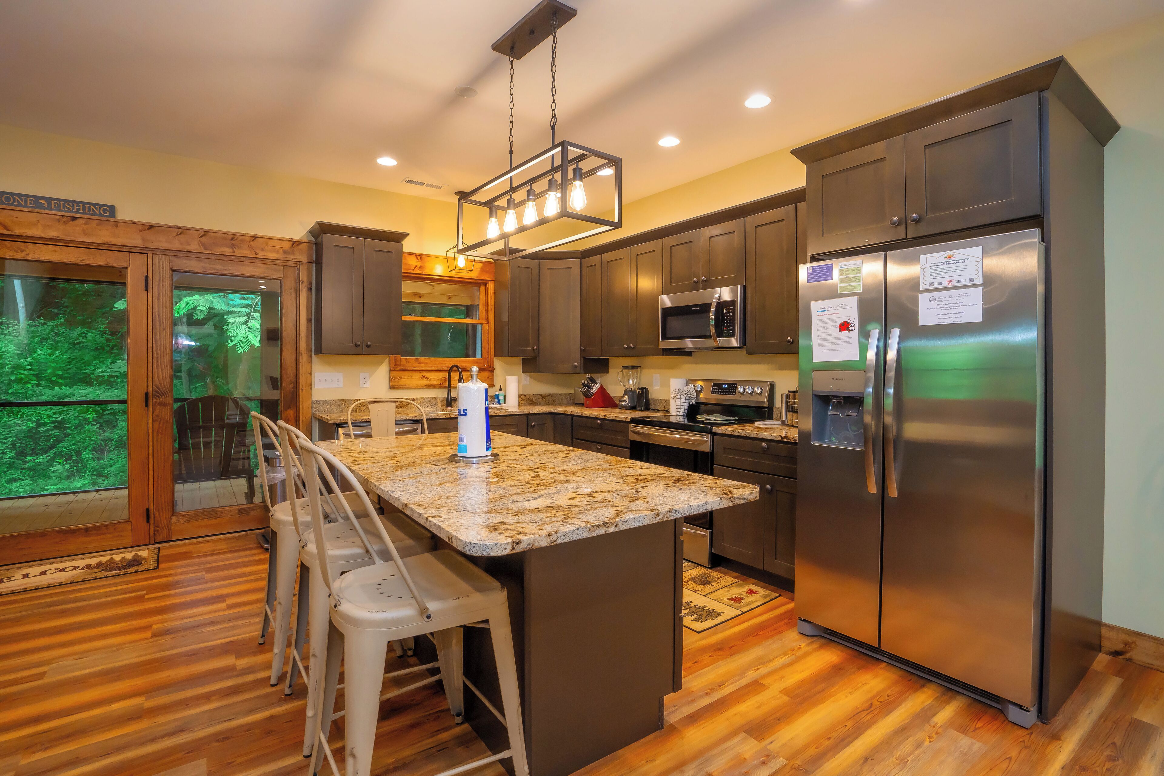 Una cocina moderna con encimeras de granito, electrodomésticos de acero inoxidable y piso de madera.