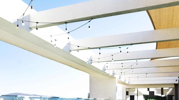 A rooftop infinity pool with a city view, lounge chairs, and string lights. - Chic Las Condes Apt: 2BR, 2BA, Pool & Gym (Santiago)