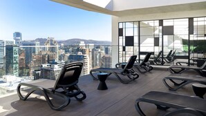 A modern lounge area with multiple lounge chairs and a large window offering a city view. - Chic Las Condes Apt: 2BR, 2BA, Pool & Gym (Santiago)