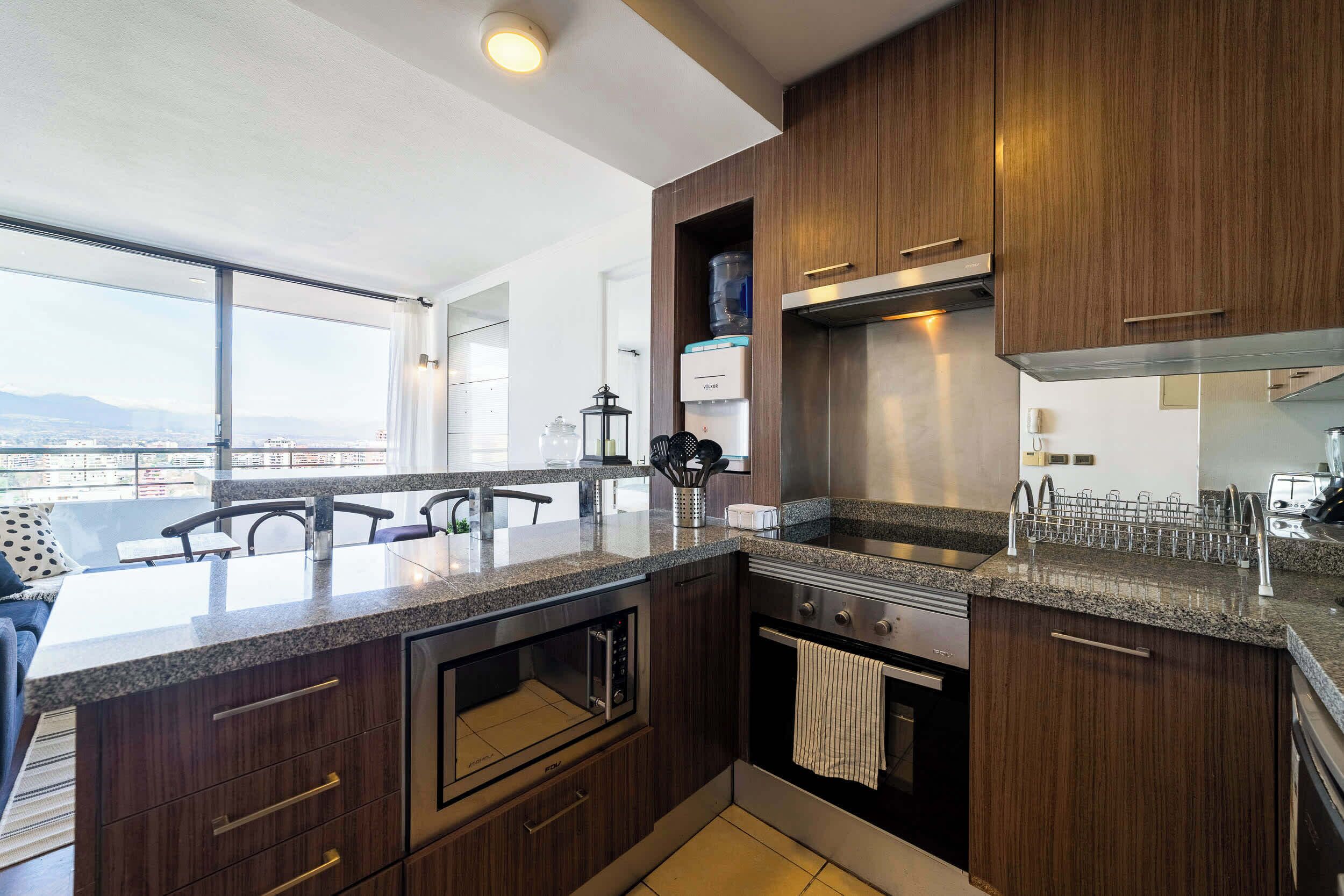 A modern kitchen with dark wood cabinets, a granite countertop, and stainless steel appliances.