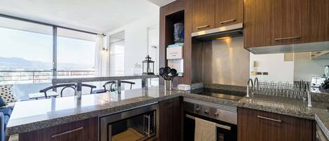 A modern kitchen with dark wood cabinets, a granite countertop, and stainless steel appliances.