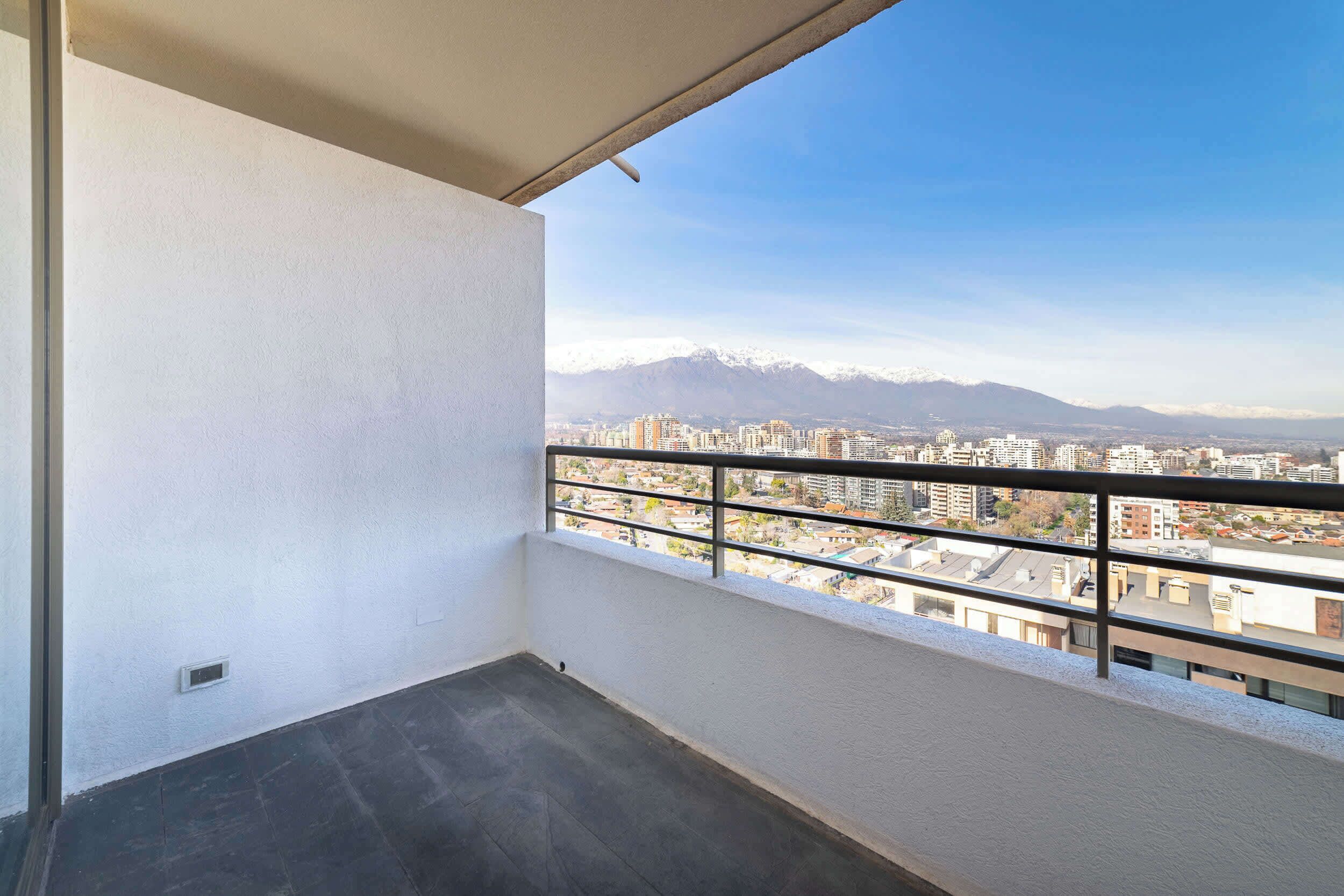 Een balkon met uitzicht op de stad, inclusief bergen in de verte.