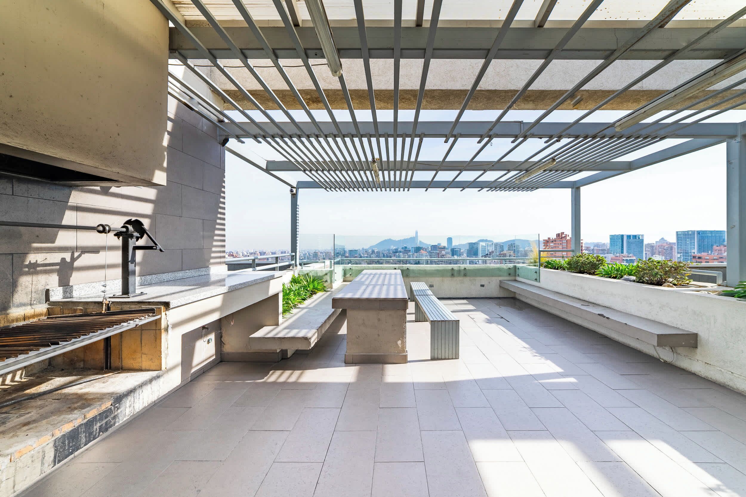Terraza en la azotea con parrilla, mobiliario y vistas a la ciudad.