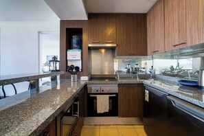 A modern kitchen with granite countertops, stainless steel appliances, and wooden cabinetry.