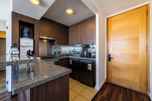 Une cuisine moderne dotée de plans de travail en granit, d’appareils électroménagers en acier inoxydable et de meubles en bois.