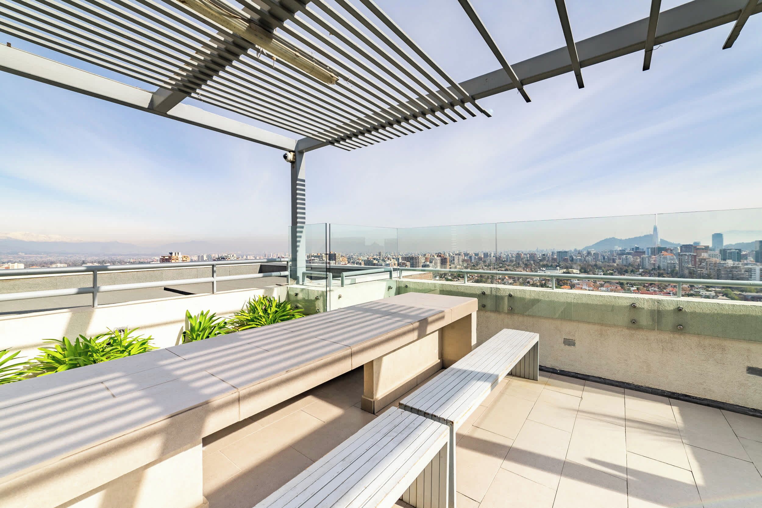 A rooftop terrace with a view of a city skyline, including a prominent building.