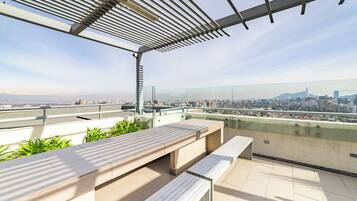 Una terraza en la azotea con vistas a un horizonte urbano, incluyendo un edificio destacado.