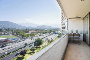 A balcony with a view of a highway, greenery, and distant mountains.