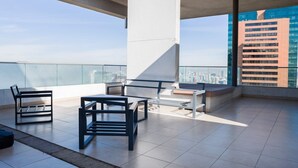 Een modern terras op het dak met een helder uitzicht op de stadshemel, met een minimalistische zithoek met een tafel en stoelen.