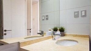 Une salle de bain avec deux lavabos, un miroir et une plante en pot.