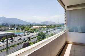 Un balcon offrant une vue sur le paysage urbain, avec ses rues, ses bâtiments et ses montagnes.