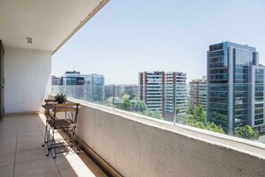 A balcony with a view of modern buildings, a small table, and a chair. - Modern 2-Bedroom, 2-Bath Apartment For 5 Guests (Las Condes)