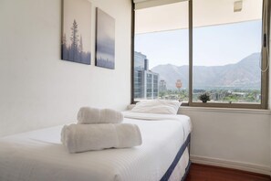 Ein Hotelzimmer mit einem Bett, zwei Handtüchern, einem Fenster mit Bergblick und zwei Wandbildern.