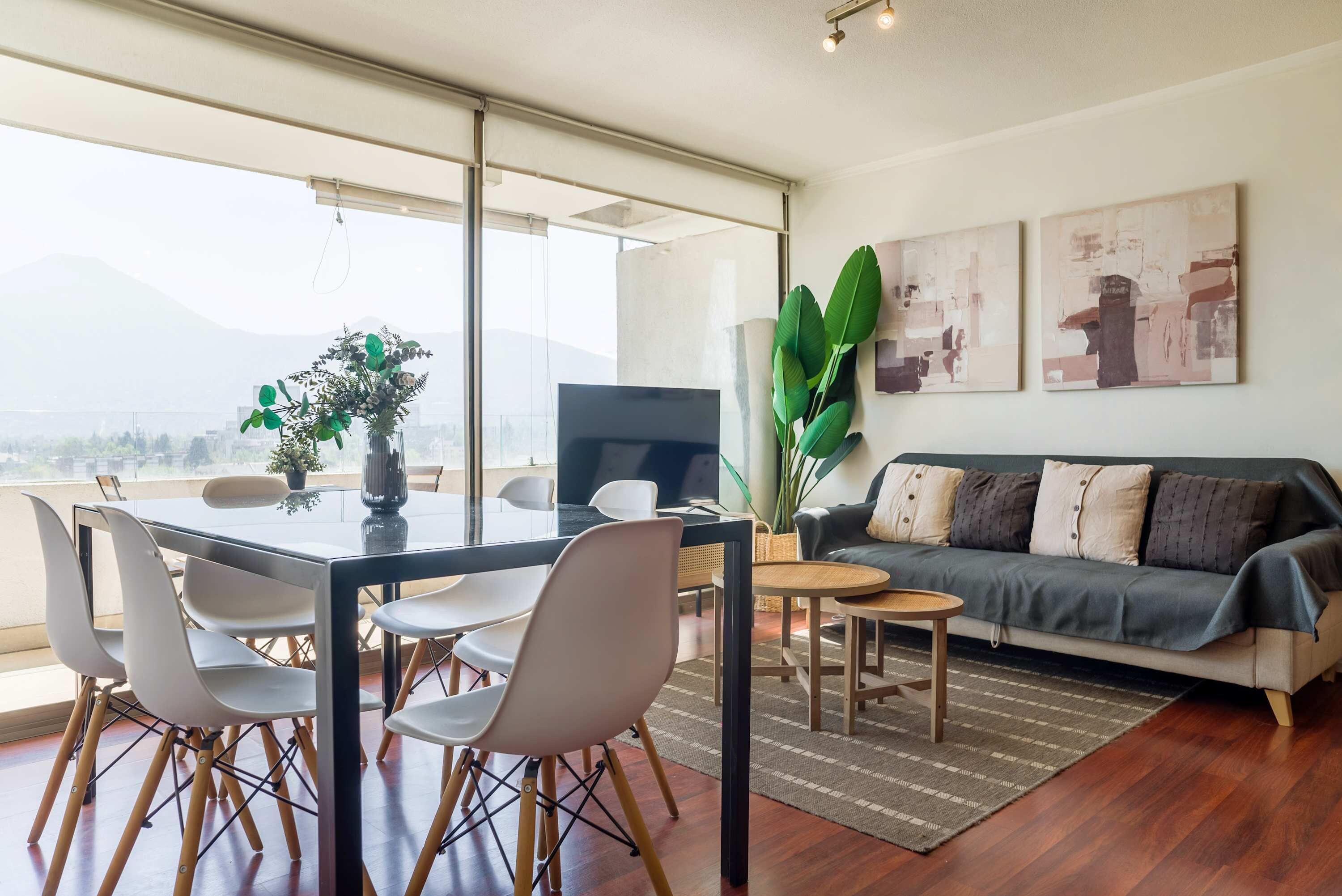 Ein modernes Wohnzimmer mit Essbereich, einem großen Fenster und Blick auf die Stadt.
