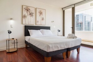 A modern bedroom with a bed, two wall-mounted lamps, and a large window with a city view. - Modern 2-Bedroom, 2-Bath Apartment For 5 Guests (Las Condes)