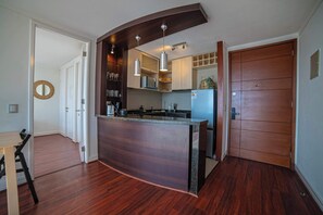 A modern kitchen with a curved island, built-in appliances, and pendant lighting. - Cozy 1BR in Prime Location: Amenities & City Views (Las Condes)