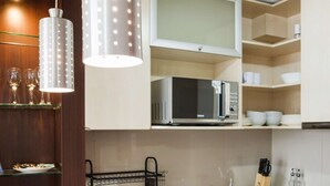 A modern kitchen with granite countertops, a built-in microwave, and pendant lighting. - Cozy 1BR in Prime Location: Amenities & City Views (Las Condes)