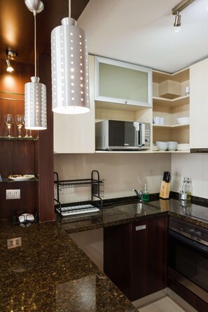 A modern kitchen with granite countertops, a built-in microwave, and pendant lighting.