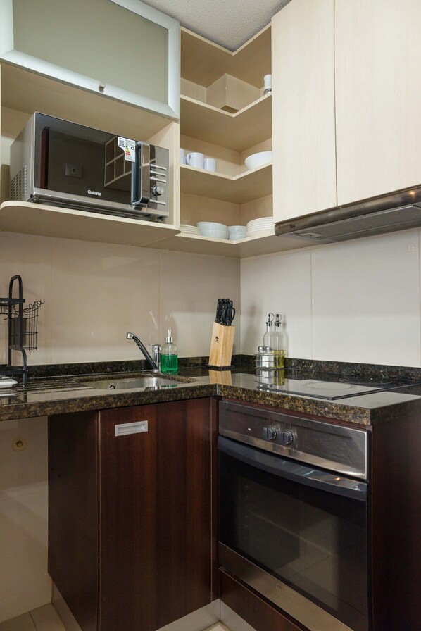 A kitchen with a built-in microwave, a sink, and a stove.