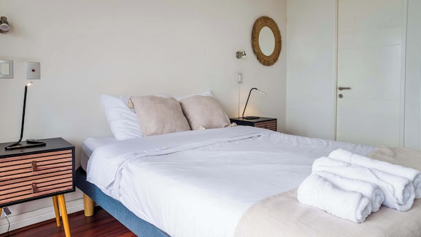 A neatly made bed with white bedding and a folded towel on the side. - Cozy 1BR in Prime Location: Amenities & City Views (Las Condes)