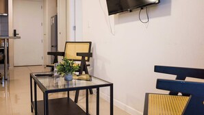 A modern living room with a flat-screen TV mounted on the wall, a glass coffee table with a plant, and a bench. - Escape to the Heart of the City with Great Views (Santiago)