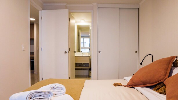 A hotel room with a bed, a bathroom visible through an open door, and a closet. - Escape to the Heart of the City with Great Views (Santiago)