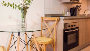 A kitchen with wooden cabinets, a glass table, and two chairs. - Downtown Stgo Studio: Balcony, WiFi & City Views! (Santiago)