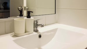 A bathroom with a white sink, mirror, and two white bottles on the counter. - Downtown Stgo Studio: Balcony, WiFi & City Views! (Santiago)