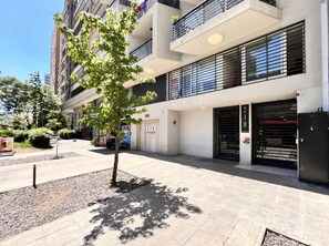 A modern building with a tree in the foreground, a gated entrance, and a clear sky.