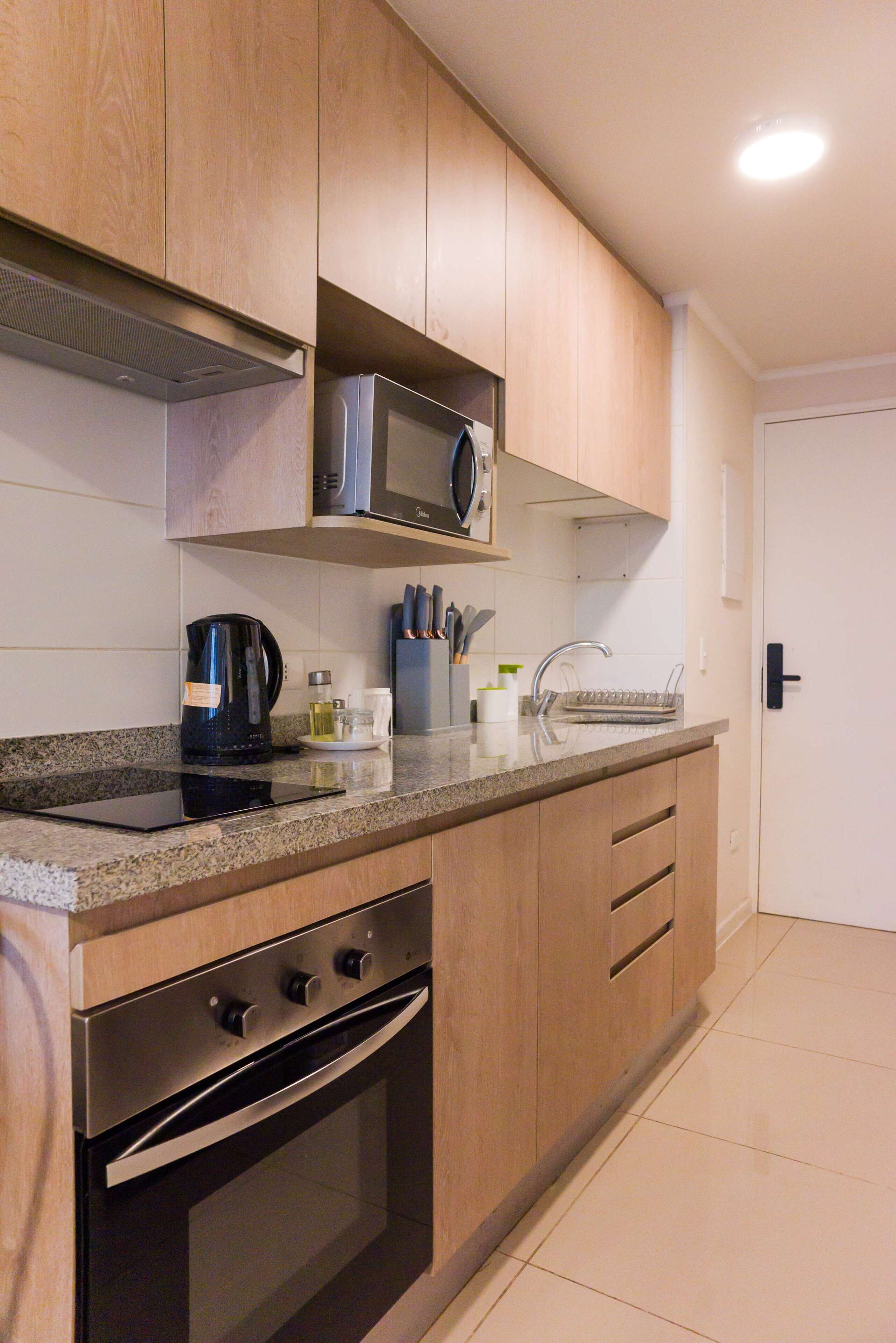 A kitchen with wooden cabinets, a microwave, a stove, a sink, and a coffee maker.