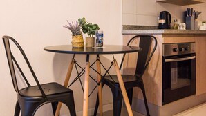Une cuisine compacte comprenant une table à manger, deux chaises, un four à micro-ondes et un four traditionnel.