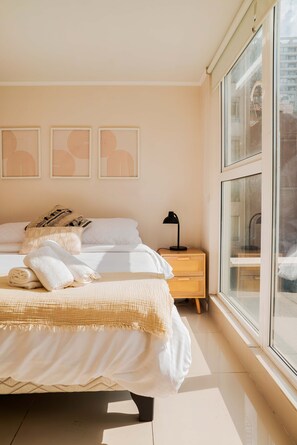 A bedroom with a bed, bedside table, and a window.