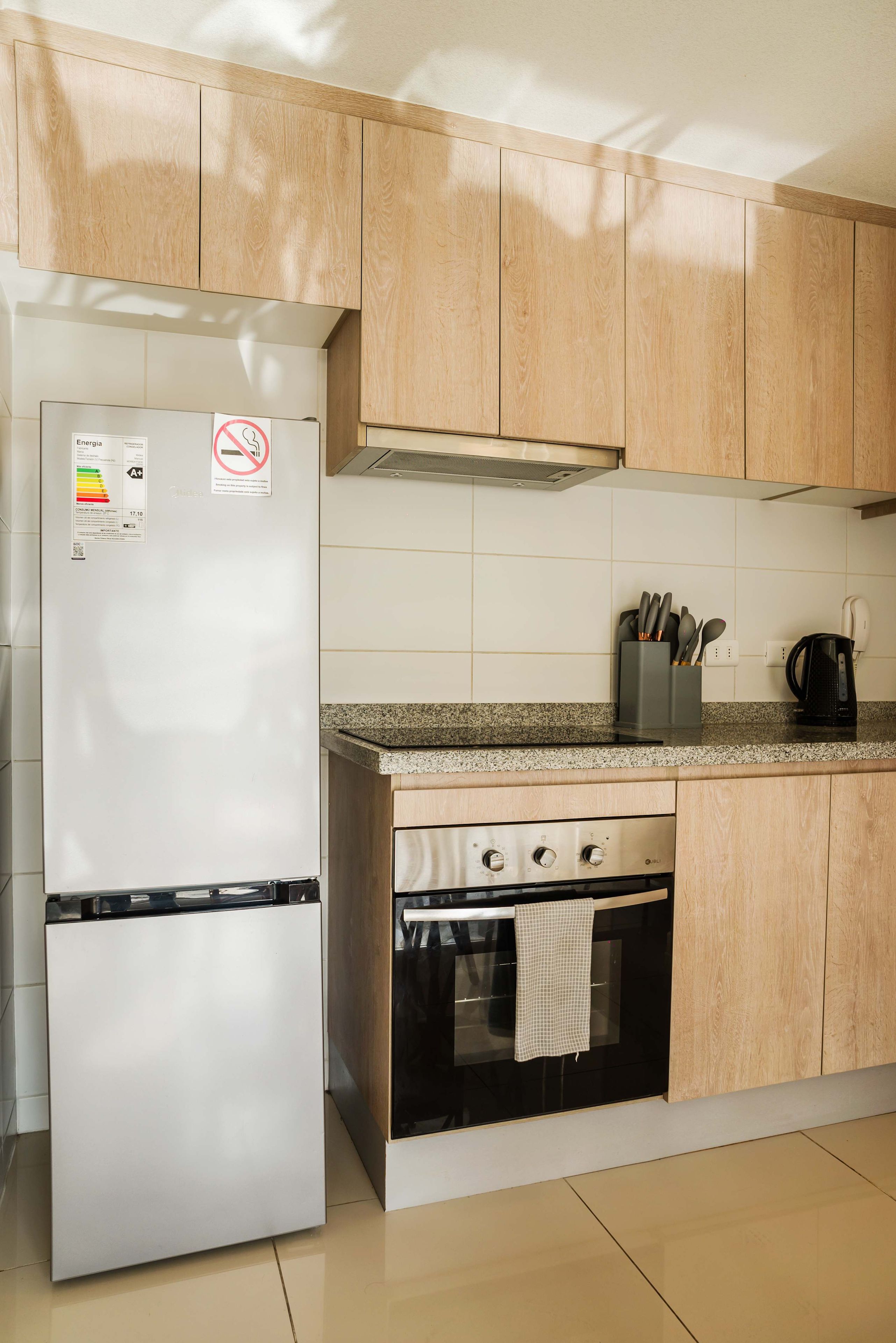 Een keuken met houten kastjes, een roestvrijstalen koelkast, een fornuis en een koffiezetapparaat.