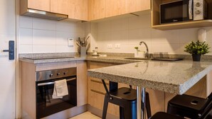 Une cuisine moderne avec des armoires en bois, un comptoir en granit, un four à micro-ondes encastré et une petite plante en pot.