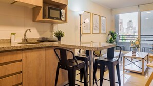 Une cuisine moderne équipée d’un four à micro-ondes, de tabourets de bar et offrant une vue sur la ville grâce à de grandes fenêtres.