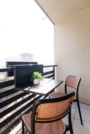 Ein Balkon mit Tisch und Stühlen, einer Topfpflanze und Blick auf ein Gebäude.