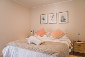 Un lit bien fait, avec des oreillers, une lampe de chevet et des décorations murales.