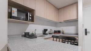 Een moderne keuken met granieten aanrecht, een ingebouwde magnetron, een koffiezetapparaat en een afdruiprek.