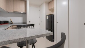 Een keuken met granieten aanrechtbladen, een zwarte koelkast en houten kastjes.