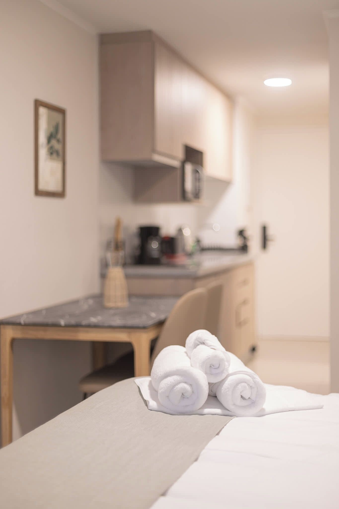 Una habitación de hotel con cama, una silla, escritorio y kitchenette.