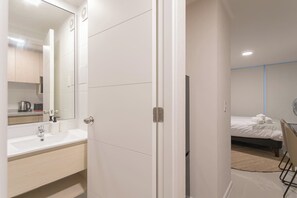A hotel room with a bathroom, a bed, and a bedside table.