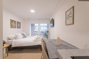 Een slaapkamer met een bed, een bureau, een stoel, een televisie en kunstwerken aan de muur.